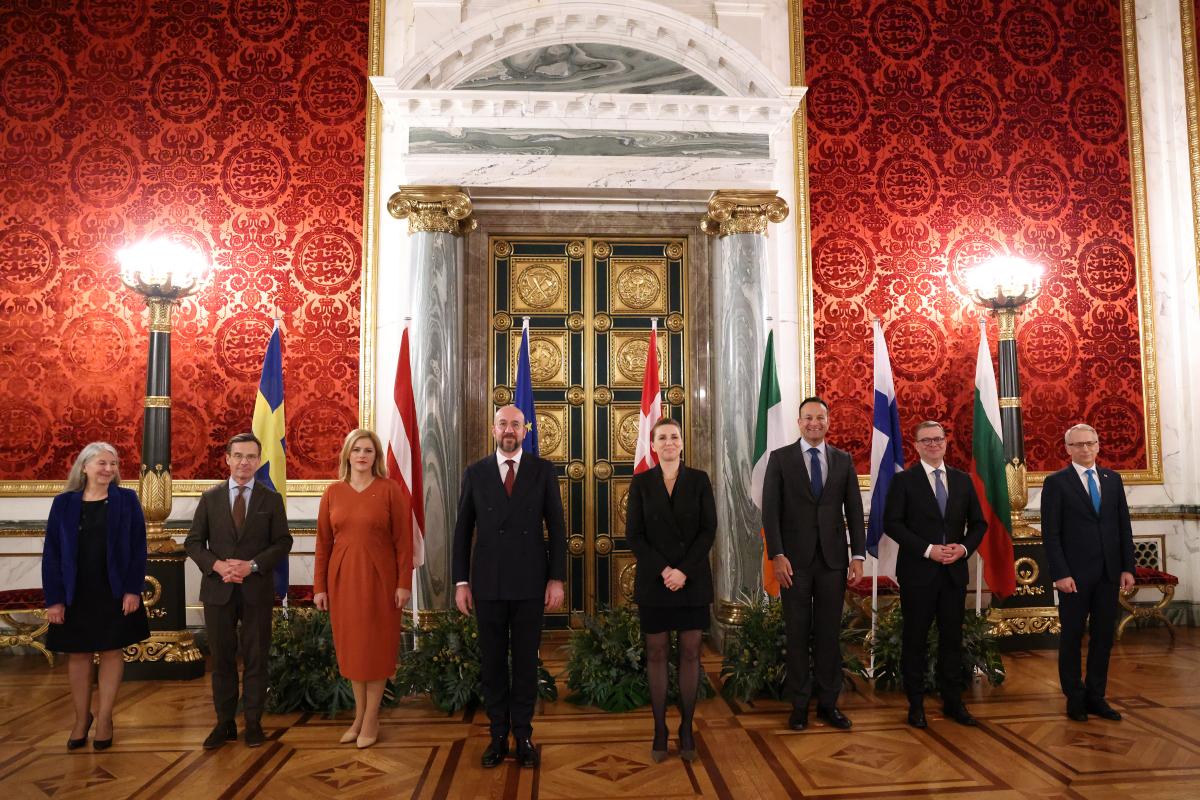The participants stand side by side in front of their countries’ flags