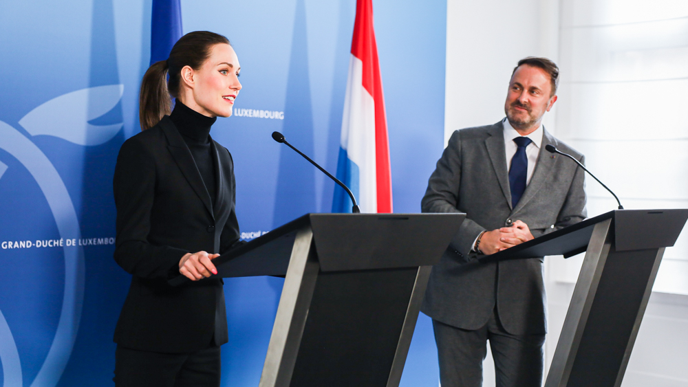 Prime Ministers Marin and Better at the press conference. Flags of Finland, the EU and Luxembourg in the background.